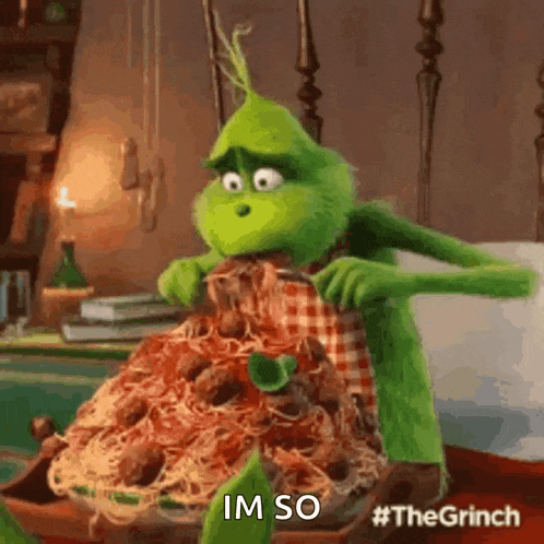 the grinch from the movie the grinch is sitting on a bed eating a pile of spaghetti and meatballs .