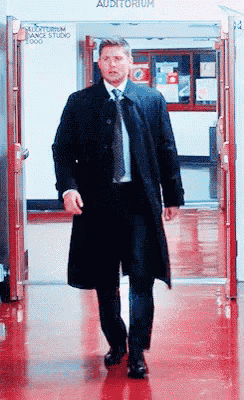 a man in a suit and tie is walking through a hallway that has the word auditorium on it