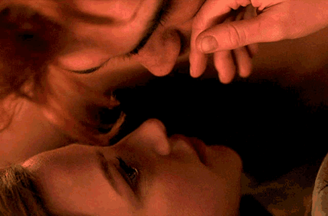 a man and a woman are touching each other 's faces with their hands