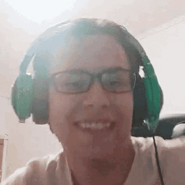 a man wearing green headphones and glasses is smiling .