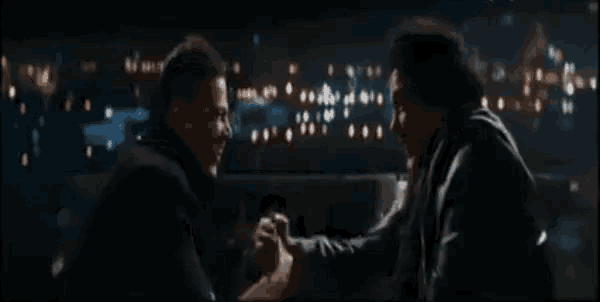 two men are sitting on a couch holding hands