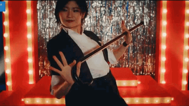 a woman in a tuxedo is holding a cane while dancing on a stage