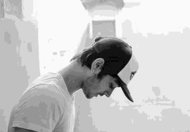 a black and white photo of a man wearing a hat and earrings .