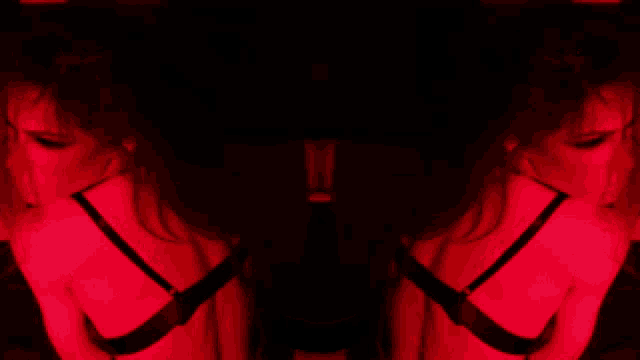 the back of a woman in a black bra is shown in red light