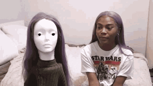 a woman with purple hair is sitting next to a white mannequin .