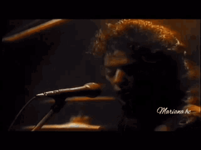 a close up of a man singing into a microphone with the name mariana written on the bottom