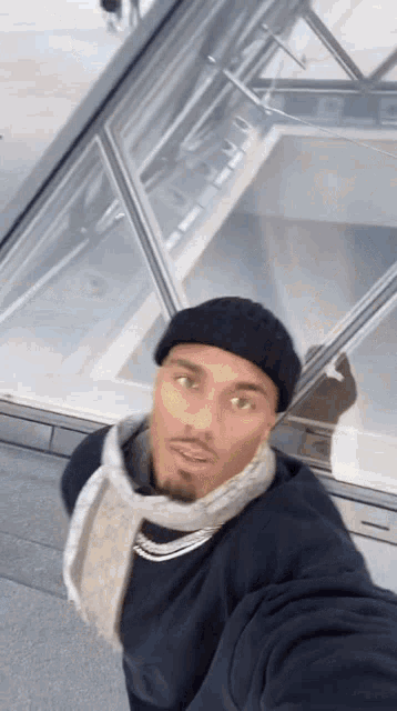a man wearing a scarf and a beanie is taking a selfie