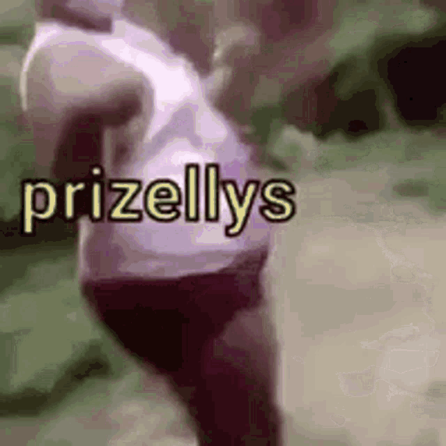 a woman in a white tank top and black shorts is standing in a field with the word prizellys written on it .