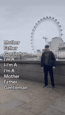 a man standing in front of a ferris wheel with the words mother father gentleman written on the side