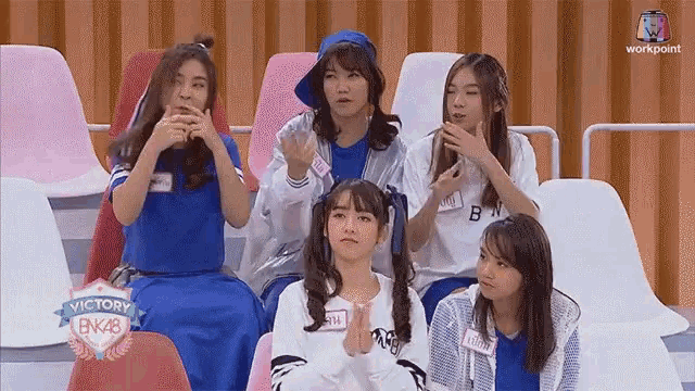 a group of girls are sitting in a stadium with a banner that says victory bk48