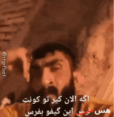 a man with a beard is talking into a microphone with arabic writing on the bottom