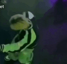 a man in a green and black jersey with the number g on it is flying through the air .