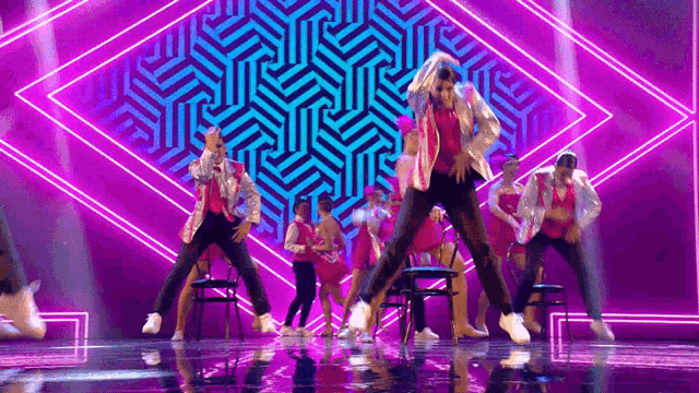 a group of dancers are performing on a stage in front of a purple and blue background .