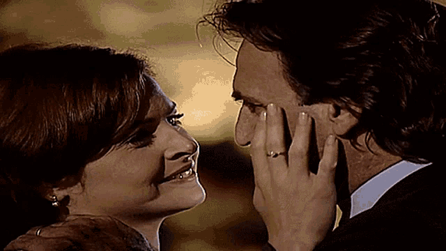 a woman with a ring on her finger touches a man 's forehead