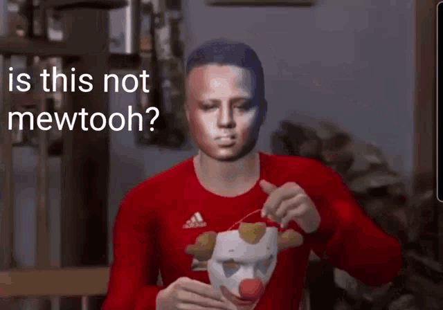 a man wearing a red adidas shirt is holding a clown mask in his hand