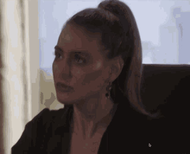 a woman with her hair in a ponytail looks at something