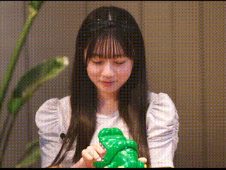 a woman in a white dress is holding a green frog .