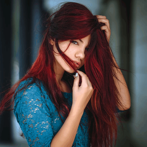 a woman with long red hair is wearing a blue lace dress