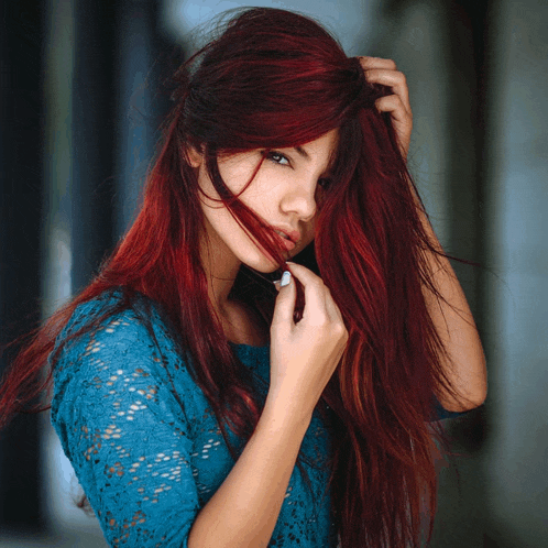 a woman with long red hair is wearing a blue lace dress