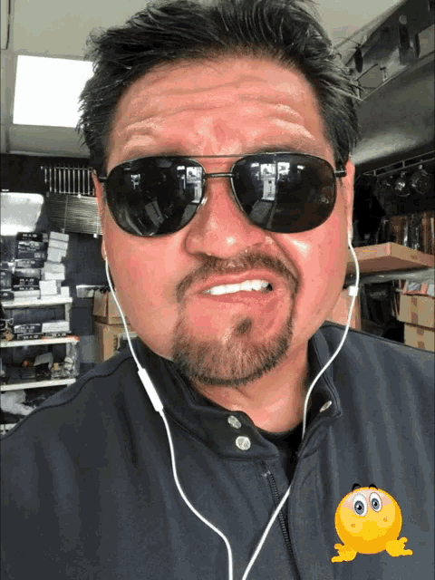 a man wearing sunglasses and ear buds is making a face