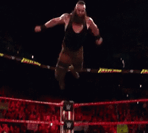 a bearded wrestler is jumping over a red ring .