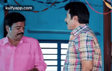two men are talking to each other in a room .