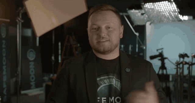 a man wearing a black shirt that says emo is standing in a dark room