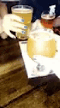 a person is holding a glass of beer on a table with a napkin .