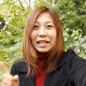 a woman is taking a selfie with trees in the background .