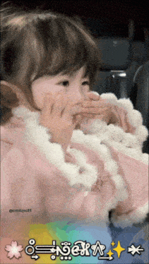 a little girl in a pink coat covering her mouth with her hands and a sticker that says ' a ' on the bottom