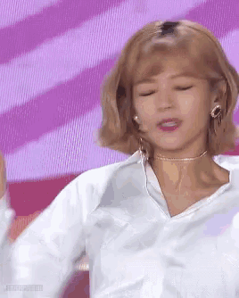 a woman wearing a white shirt and a choker is dancing on a stage .