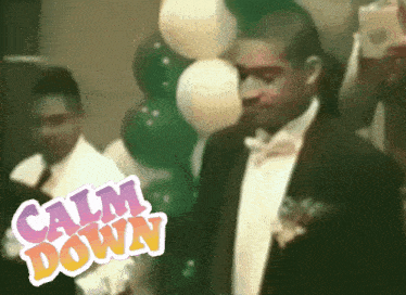 a man in a tuxedo stands in front of a bunch of balloons with the words calm down on the bottom