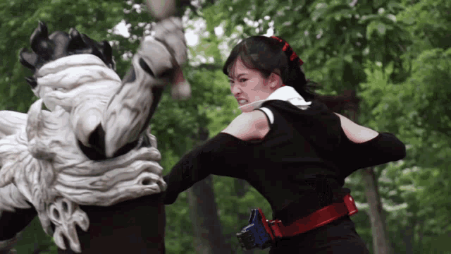a woman is fighting a monster in a park
