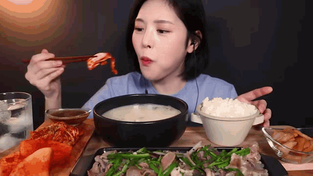 a woman is eating food with chopsticks and a bowl of soup