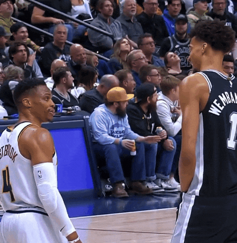 a basketball player with the number 1 on his jersey stands next to another player