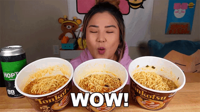 a woman eating three cups of noodles with the word wow written on the bottom
