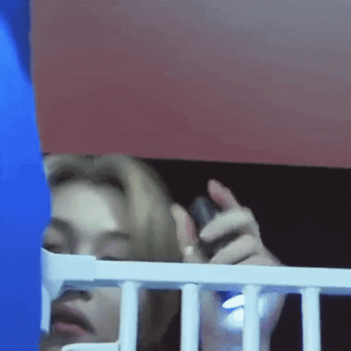 a person behind a white fence holding a cell phone