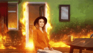 a woman is sitting in front of a fire in a burning room .