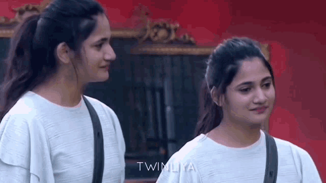 two women are standing next to each other and the word twinliya is on the bottom left