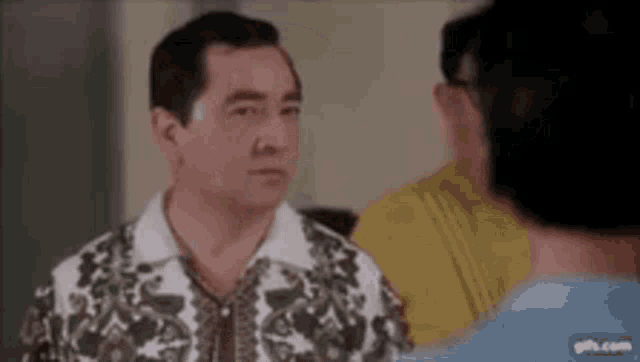 a man in a floral shirt is talking to two other men .