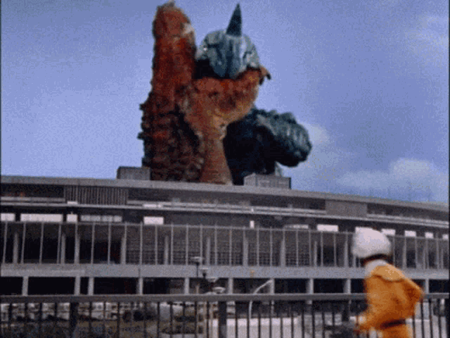 a man in a yellow jacket stands in front of a large monster