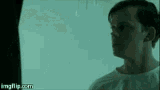 a man in a hospital gown is standing in a dark room .