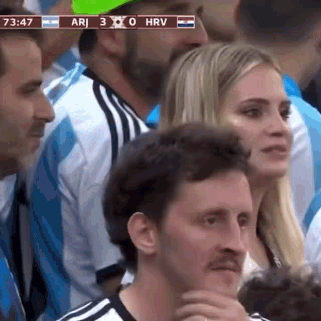 a group of people are watching a soccer game and the score is ari 3 0 hrv