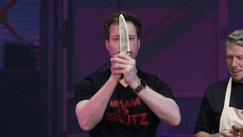 a man holding a knife in front of a sign that says tz