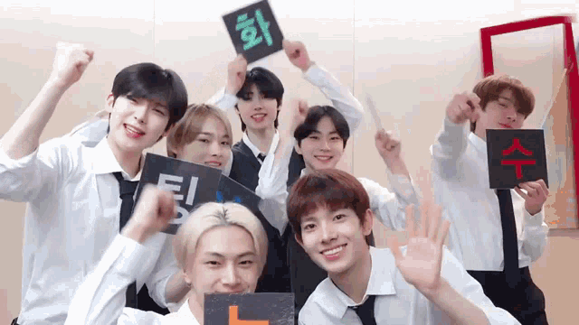 a group of young men in white shirts and ties are posing for a picture while holding signs .