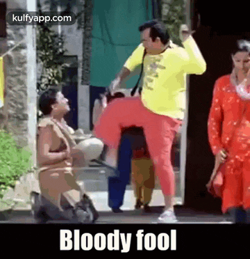 a man in a yellow shirt and red pants is kicking a woman in the knee .