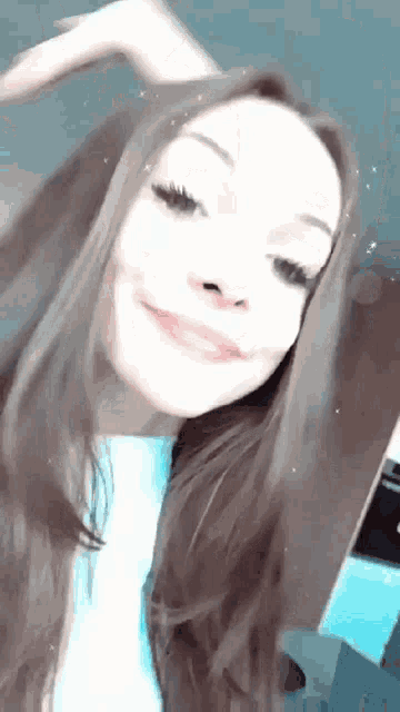 a young woman with long brown hair is taking a selfie and smiling .