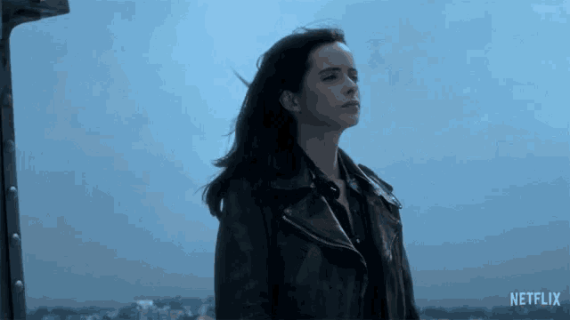 a woman in a black leather jacket is standing in front of a netflix sign