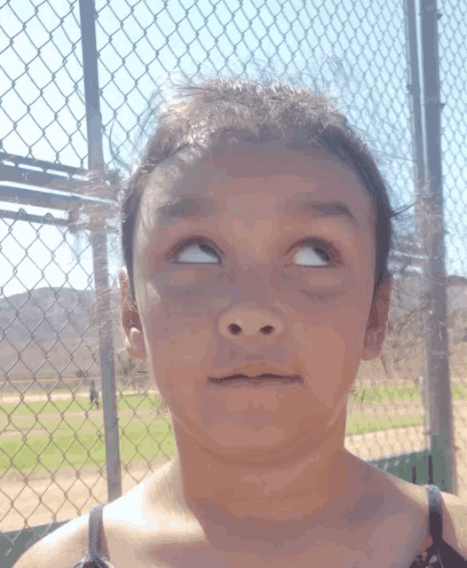 a young girl making a funny face in front of a fence