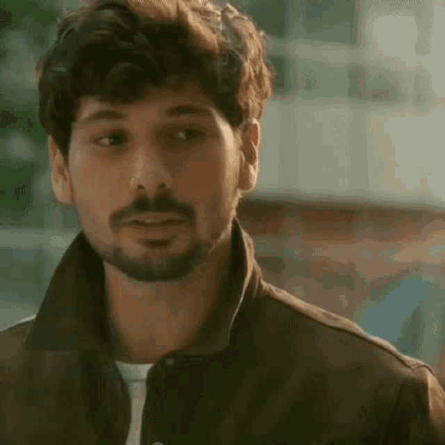 a close up of a man with a beard wearing a jacket .